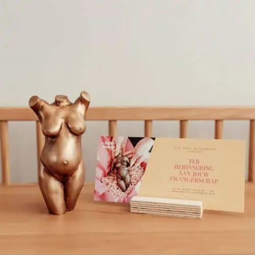 Bronzen zwangerschapsbeeldje op een houten bankje met een kaartje ‘Ter herinnering aan jouw zwangerschap’ van Mijn Baby Buikje